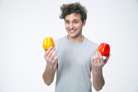 Smiling man holding peppers over gray backgroundの写真素材