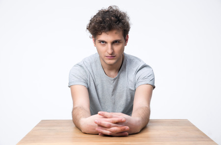 Handsome young man sitting at the table and looking at cameraの写真素材