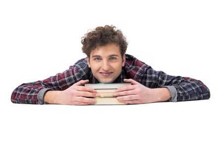 Smiling young man lying on the table with booksの写真素材
