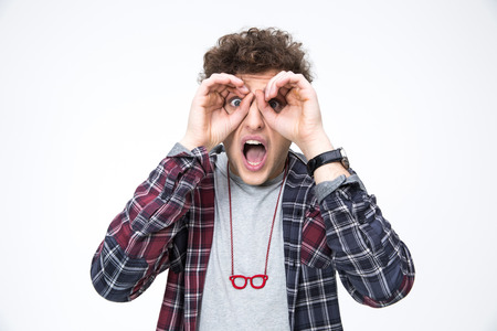 Surprised young man looking through fingersの写真素材