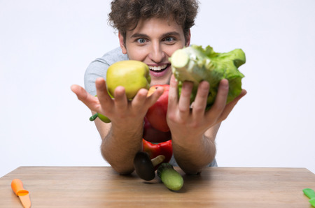 Happy man sitting at the table with vegetablesの写真素材