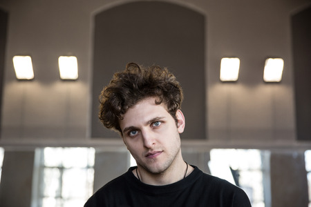 Portrait of a young serious man with curly hair