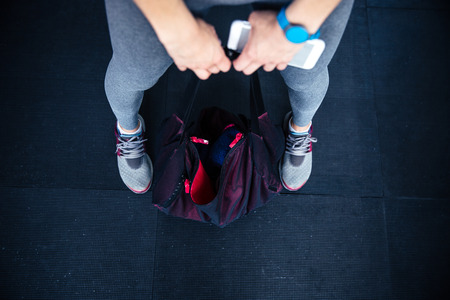 Closeup image of woman holding fitness bag and smartphoneの写真素材