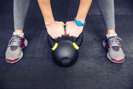 Closeup image of a woman working out with kettle ball at gymの写真素材