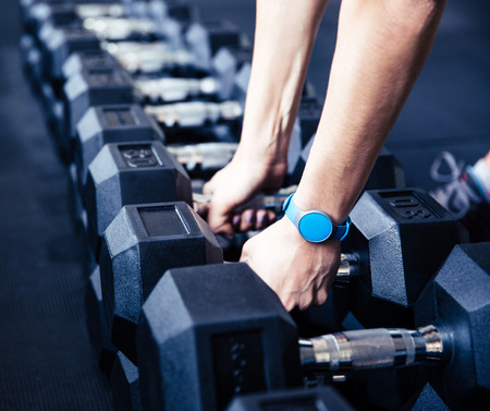 Woman takes a dumbbell at gymの写真素材