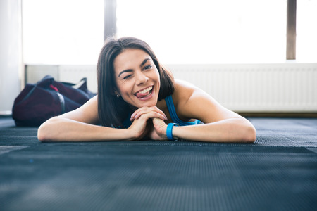 Woman lying on the floor. showing her tongue and winking. Looking at cameraの写真素材