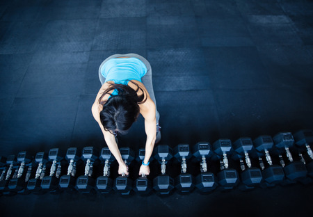 Woman takes a dumbbell at gymの写真素材