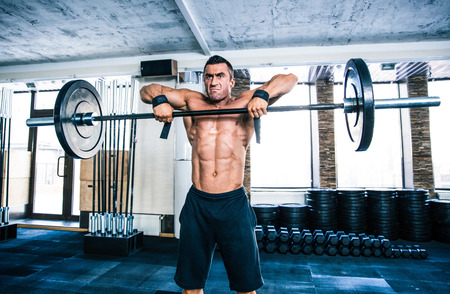 Handsome fitness man lifting barbell at gymの写真素材