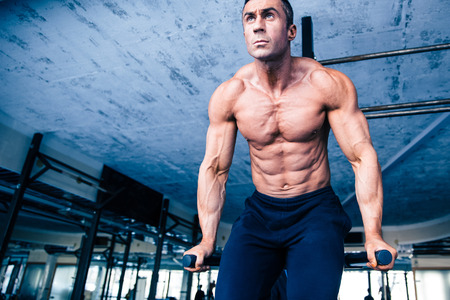 Handsome muscular man workout on bars in crossfit gym
