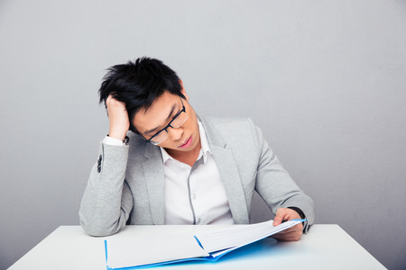 Businessman sitting at the table and reading papers in officeの写真素材