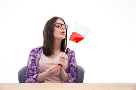 Young pretty woman in glasses blowing on the Polish flag over white backgroundの写真素材
