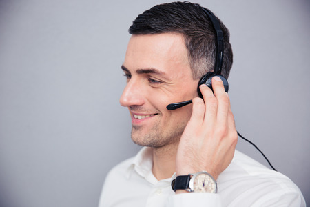 Happy businessman with headphones standing over gray backgorund and looking away