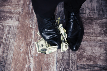 Closeup image of a businessman standing on the US dollar billsの写真素材