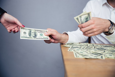 Closeup image of a male hand giving money to female hand