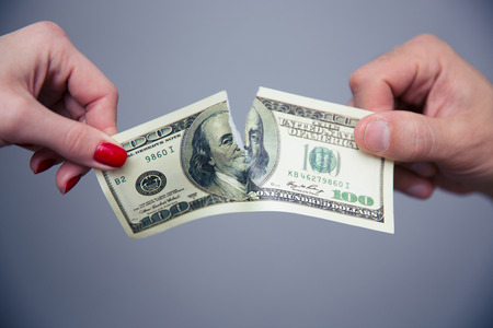 Concept image of a female and male hand dividing money over gray backgroundの写真素材