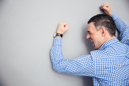 Angry man shouting and hitting gray wallの写真素材