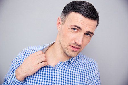 Man loosing his shirt to relax a bit after hard work over gray background. Looking at cameraの写真素材