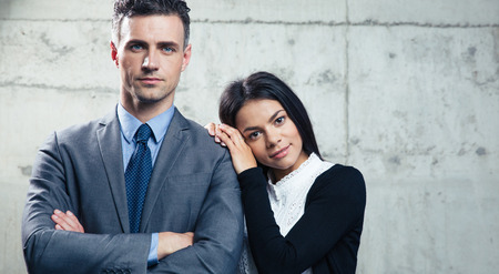 Portrait handsome businessman and beautiful businesswoman standing together over concrete wall and...
