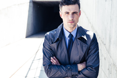 Portrait of a handsome businessman standing outdoors with arms folded and looking at cameraの写真素材
