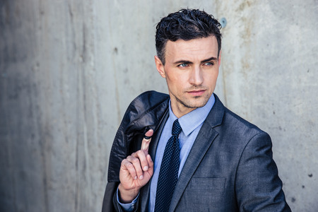 Portrait of a pensive businessman standing over concrete wall and looking awayの写真素材