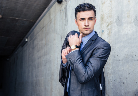 Portrait of a handsome businessman standing over concrete wallの写真素材