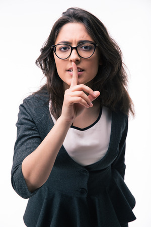 Businesswoman in glasses showing finger over lips isolated on a white background. Be quiet!!! Looking at cameraの写真素材