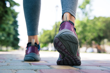 Footwear on female feet running on road outdoors