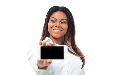 Smiling afro american businesswoman showing blank smartphone screen isolated on a white background. Looking at cameraの写真素材