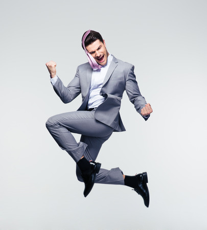 Happy businessman jumping in air over gray backgroundの写真素材