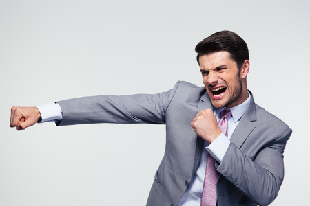 Angry businessman fighting and shouting over gray backgroundの写真素材