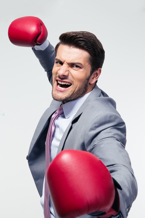 Angry businessman with boxing gloves over gray backgroundの写真素材