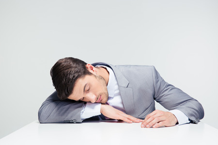 Businessman sleeping on the table over gray backgroundの写真素材