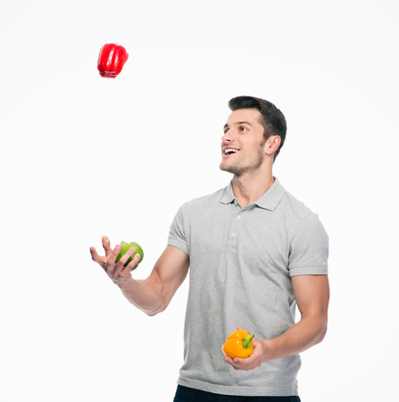 Happy young man juggling pepper isolated on a white backgroundの写真素材