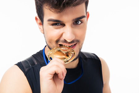 Sports man biting medal isolated on a white background. Looking at cameraの写真素材