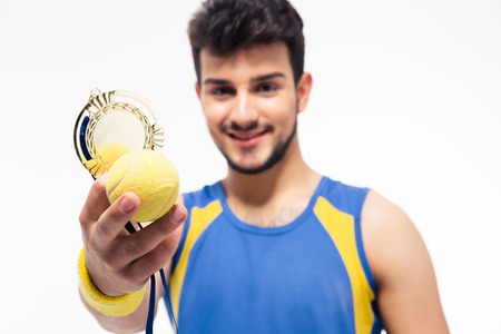Happy sports man holding medal and tennis ball isolated on a white background. Focus on tennis ballの写真素材