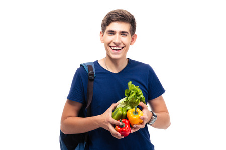 Cheerful male student holding vegetables and looking at camera isolated on a white backgroundの写真素材
