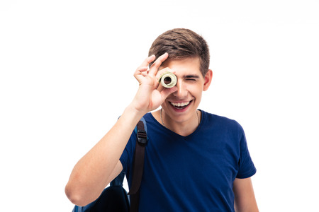 Smiling male student looking at camera through money isolated on a white backgroundの写真素材