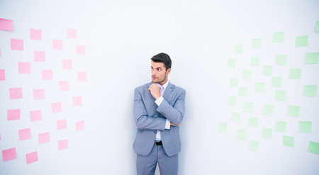 Handsome businessman standing near wall with stickers in officeの写真素材