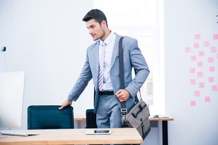 Portrait of a confident businessman with bag standing in officeの写真素材