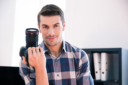 Happy young man in shirt holding photo camera