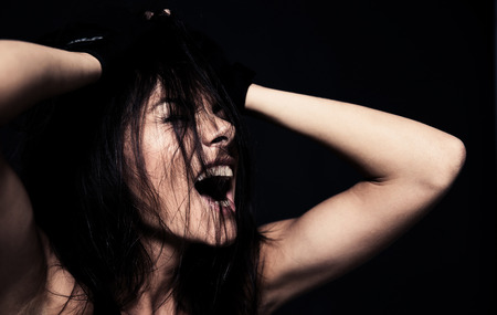 Portrait of a young woman shouting over black backgroundの写真素材