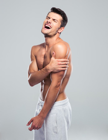 Man having pain in hand over gray backgroundの写真素材