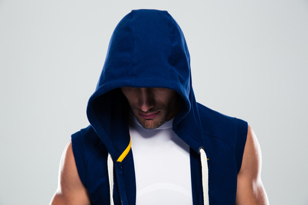 Portrait of a sportsman in hood standing over gray backgroundの写真素材