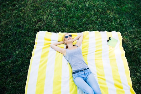 Smiling young woman lying on the mat in parkの写真素材