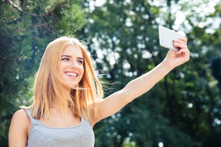 Happy young woman making selfie photo outdoorsの写真素材