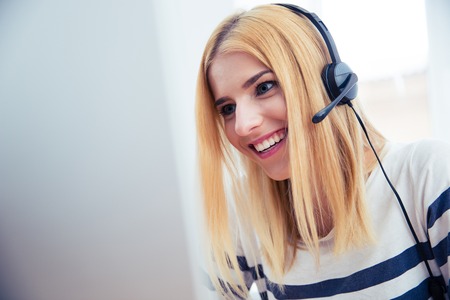 Happy young girl in headset using desktop computer in officeの写真素材