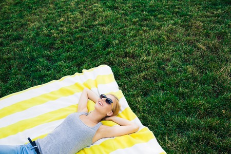 Happy young girl resting on lawn outdoorsの写真素材