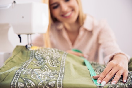 Haooy female tailor working in workshop. Focus on clothの写真素材