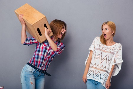Two women quarrel over gray backgroundの写真素材