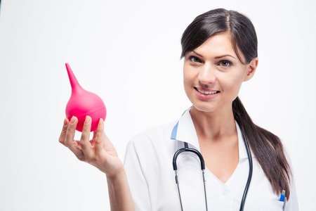 Happy female doctor holding enema isolated on a white background. Looking at cameraの写真素材